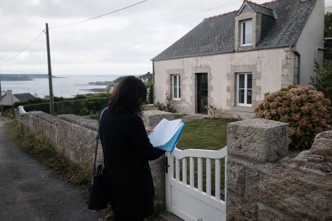 Maison individuelle en pierre dans une commune du Finistère, avec jardin et rue résidentielle en arrière-plan.
