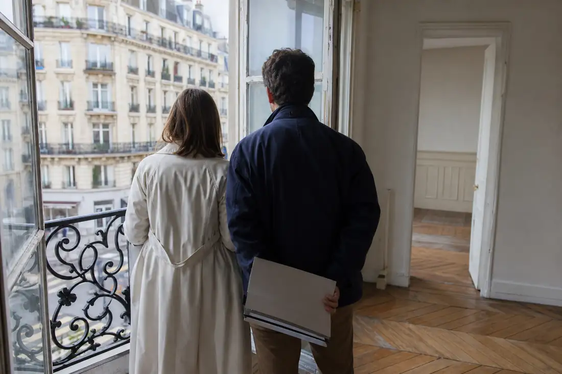 Couple examinant un appartement ancien à rénover lors d’une visite avant une offre d’achat.