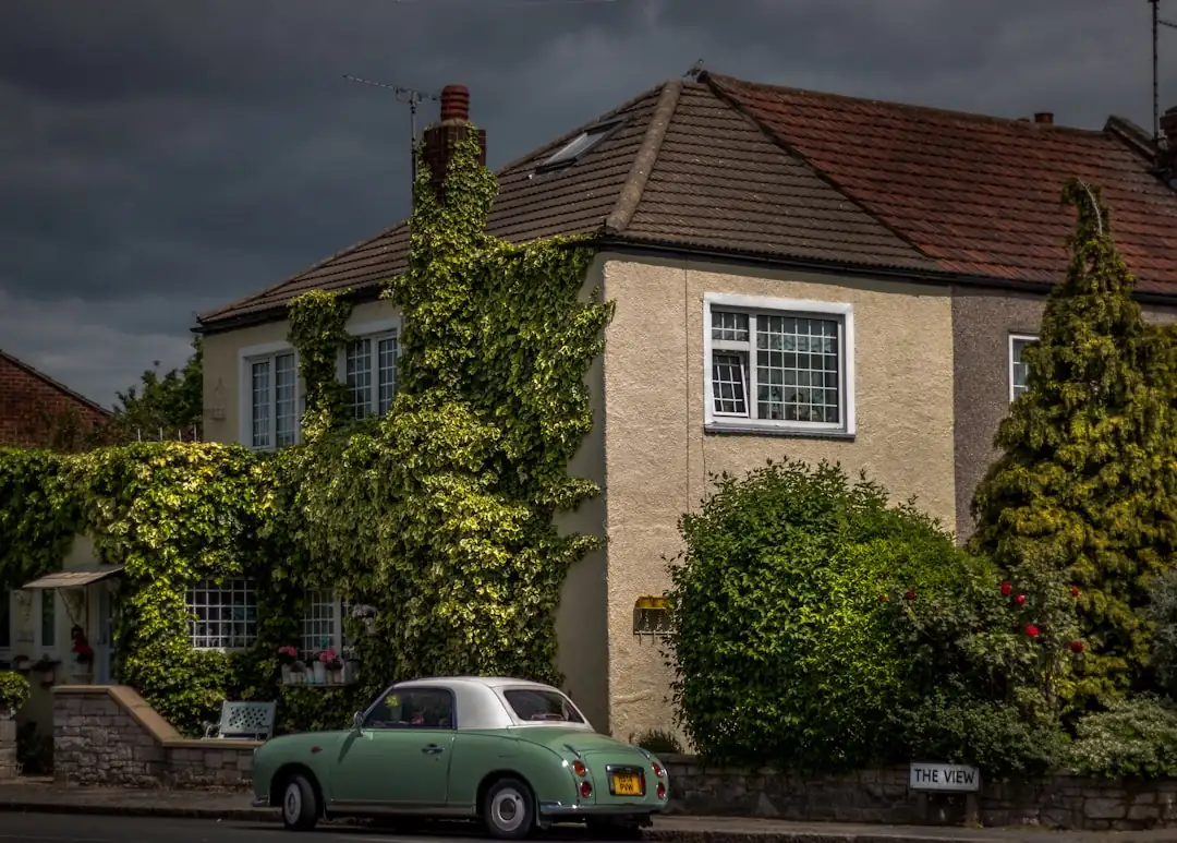 Propriétaire devant une maison française, dossier immobilier en main, dans un quartier en rénovation urbaine.