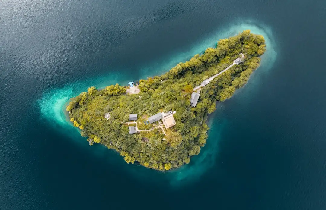 Maison en pierre sur une île française, avec végétation littorale et port visible au loin.
