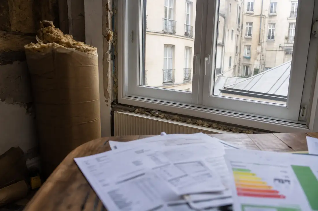 Appartement ancien en rénovation énergétique avec matériaux d’isolation et documents de gestion locative sur une table.