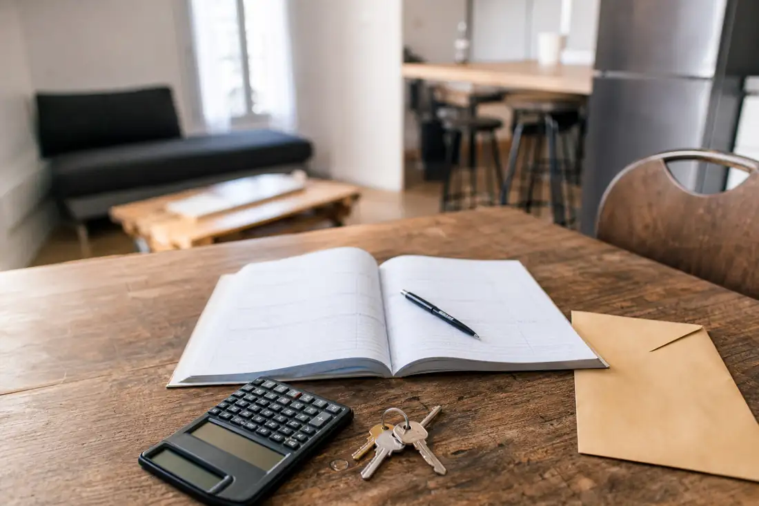 Table d’un logement locatif avec clés, calculatrice et documents de gestion évoquant un impayé de loyer.