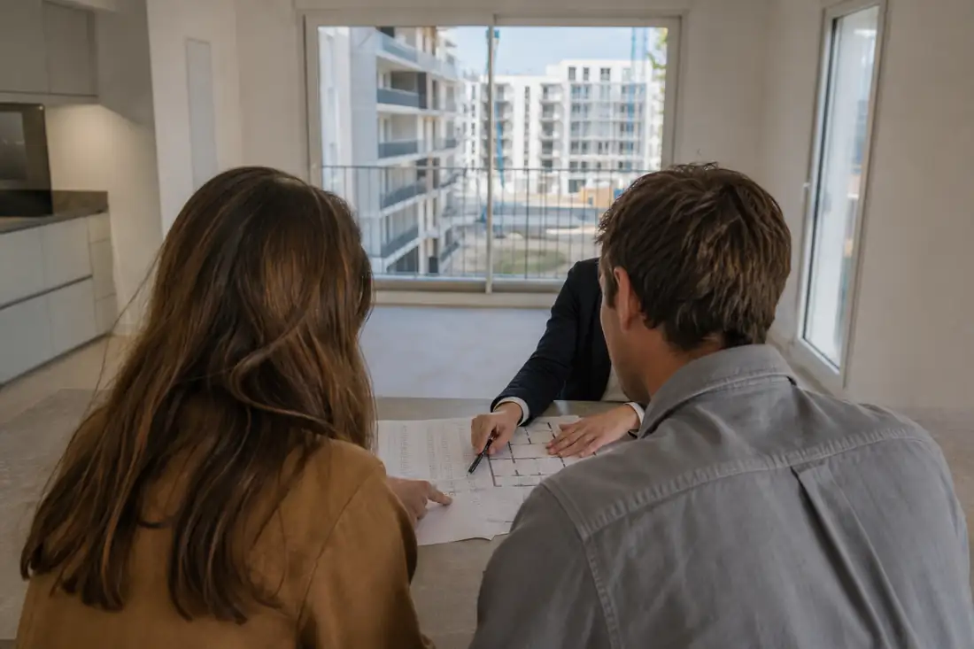 Couple examinant un plan de financement dans un appartement neuf lumineux avant la remise des clés.