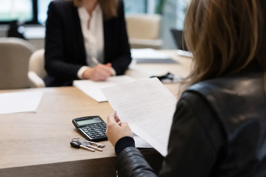 Locataire vérifiant le détail des honoraires sur un bail de location devant une agence immobilière.