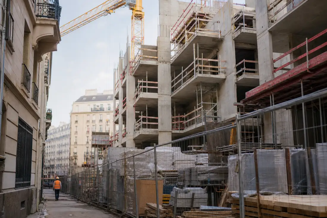 Grue et immeubles en construction au bord d’un quartier résidentiel français sous une lumière matinale.