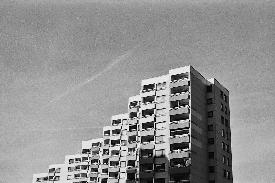 Immeubles récents et bâtiment ancien rénové dans un quartier urbain, avec chantier résidentiel en arrière-plan.