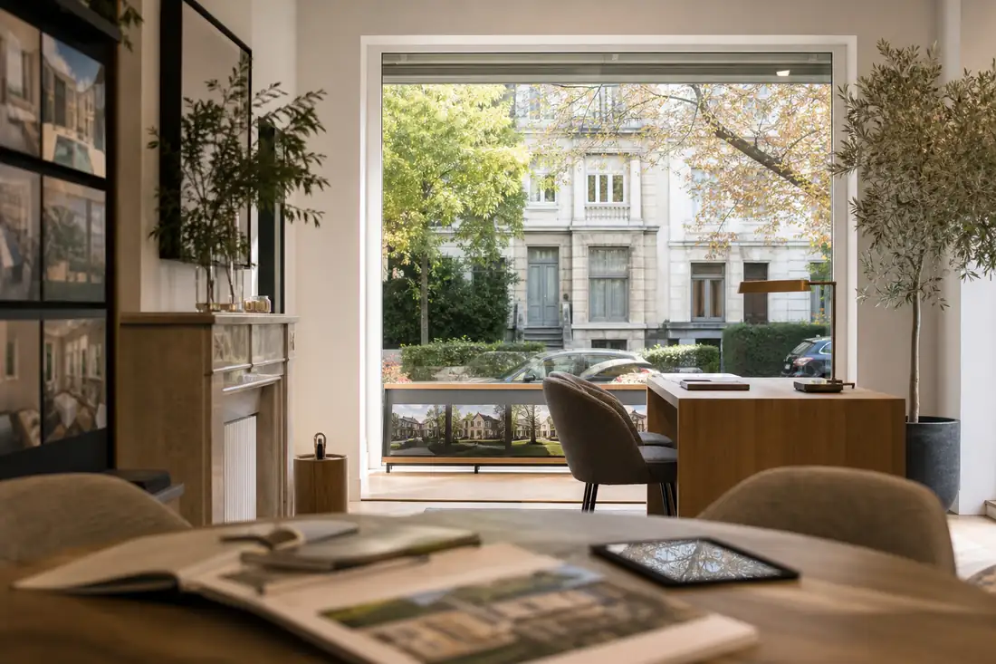 Intérieur d’agence haut de gamme donnant sur une rue résidentielle arborée de Waterloo, dans le Brabant wallon.