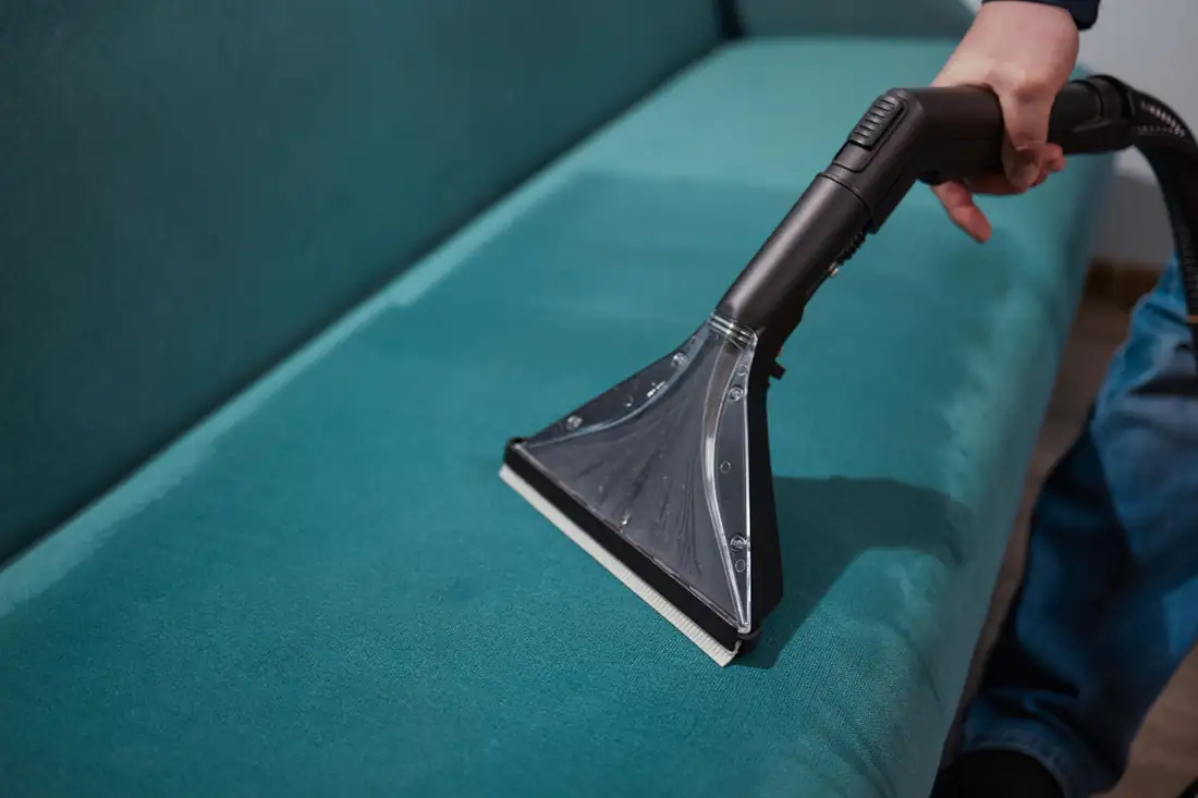 Nettoyage à la vapeur des joints de carrelage dans une salle de bains avec une brosse et une microfibre.
