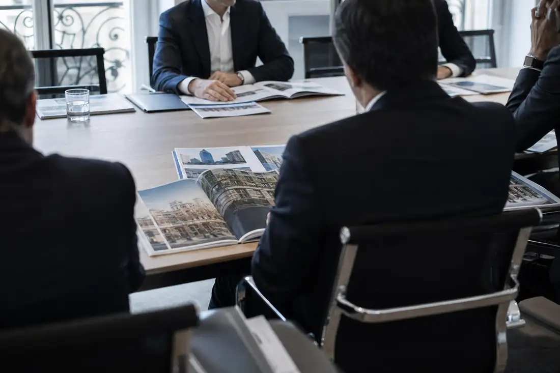 Réunion de dirigeants autour de dossiers immobiliers dans une salle de conseil d’une société de gestion.