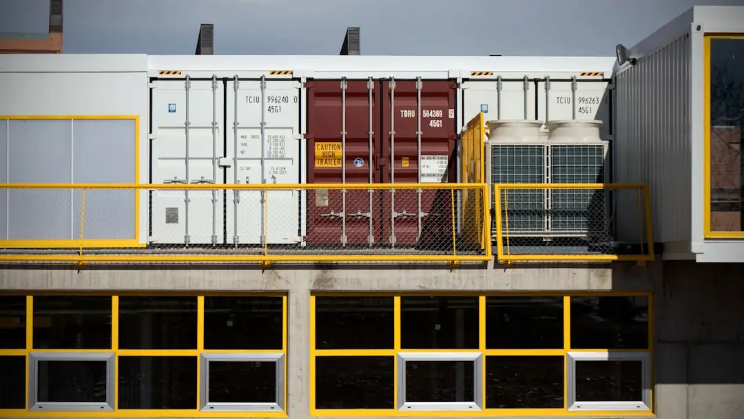Allée intérieure d’un centre de self-stockage avec rangées de box sécurisés et chariot de déménagement.