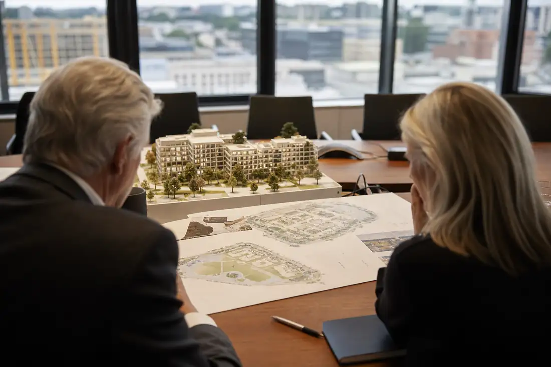 Réunion d’investissement devant une maquette d’immeuble et des plans de développement immobilier.