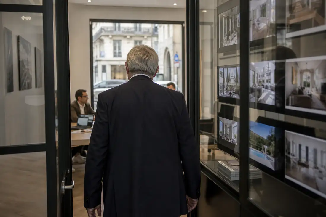 Réunion de direction dans une agence immobilière autour d’outils numériques et de dossiers clients.