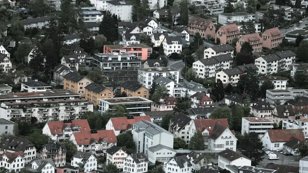 Gestionnaire examinant un portefeuille immobilier suisse devant des immeubles résidentiels et un paysage alpin.