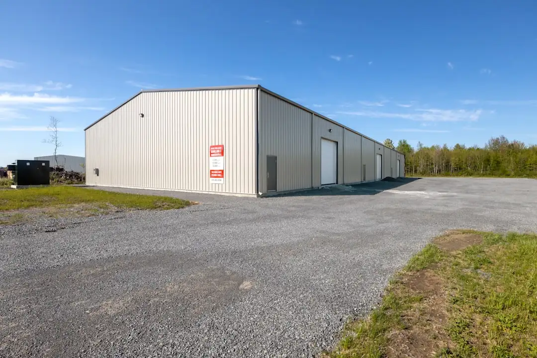 Centre de stockage en zone d’activités avec quais de chargement et portail sécurisé sous lumière matinale.
