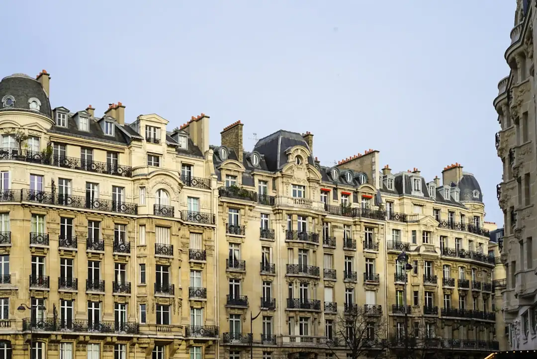 Intérieur haussmannien parisien lors d’une visite, avec parquet, grandes fenêtres et dossiers de vente.