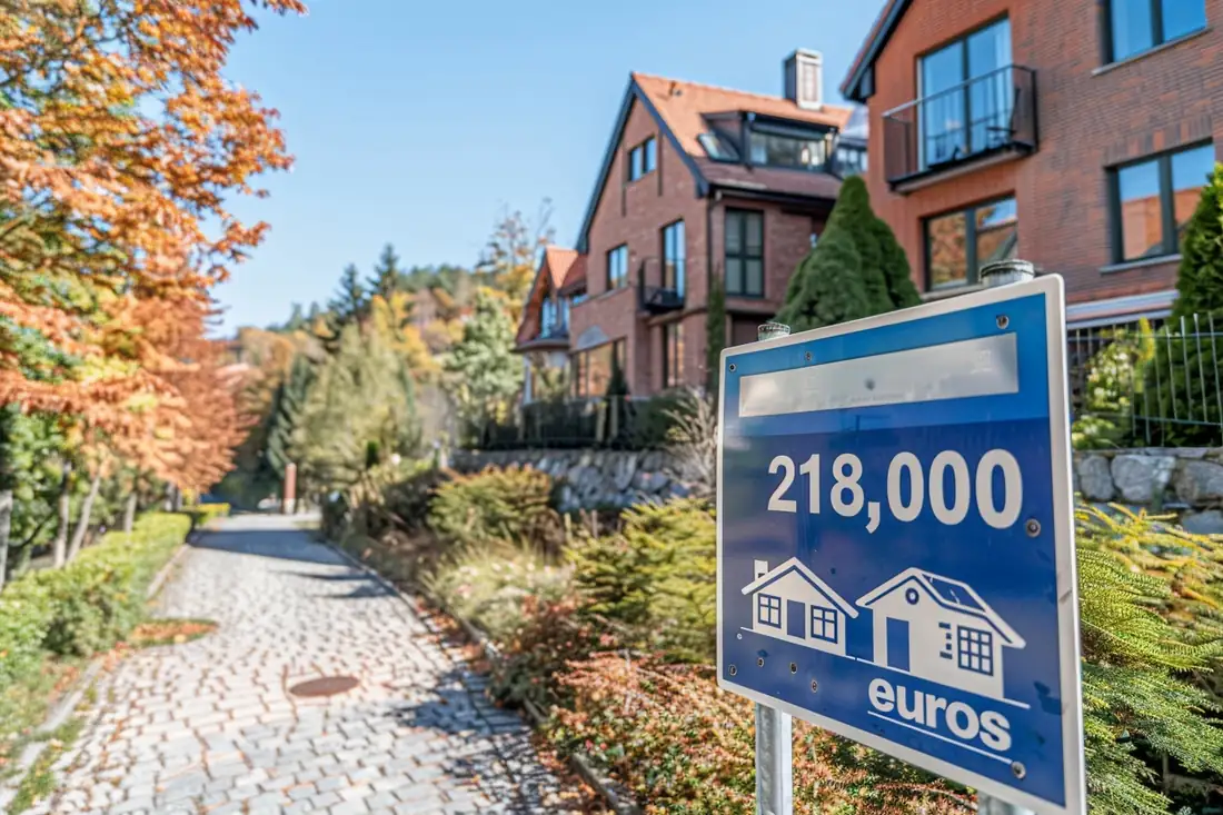 Couple examinant un budget d’achat immobilier avec plans, calculatrice et documents financiers sur une table.