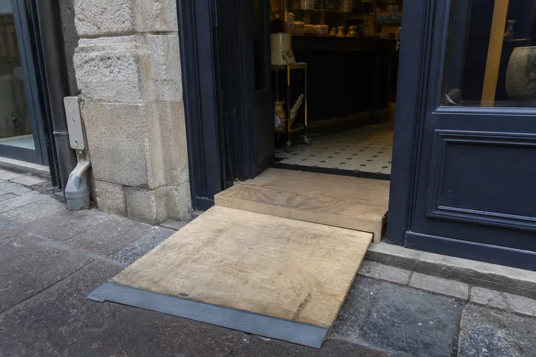 Entrée d’un commerce ancien avec une rampe d’accessibilité installée devant la porte