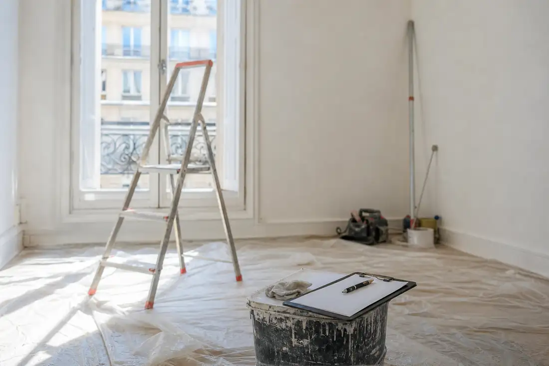 Pièce fraîchement rénovée en fin de chantier, bâche de protection au sol et outils rangés