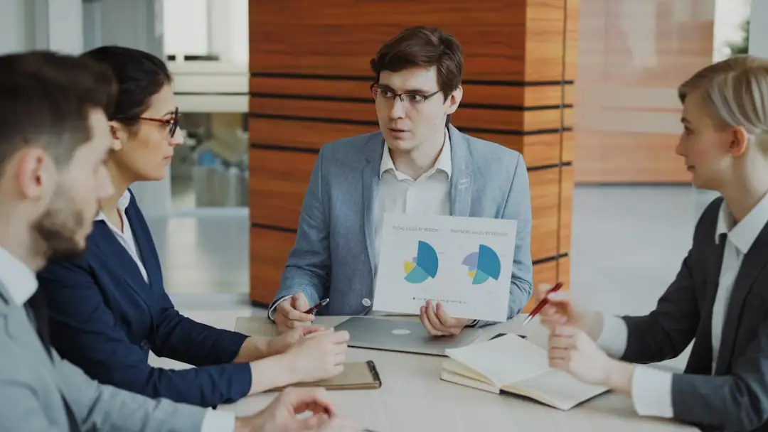 Documents financiers et calculatrice sur une table, avec un immeuble de bureaux flou en arrière-plan.