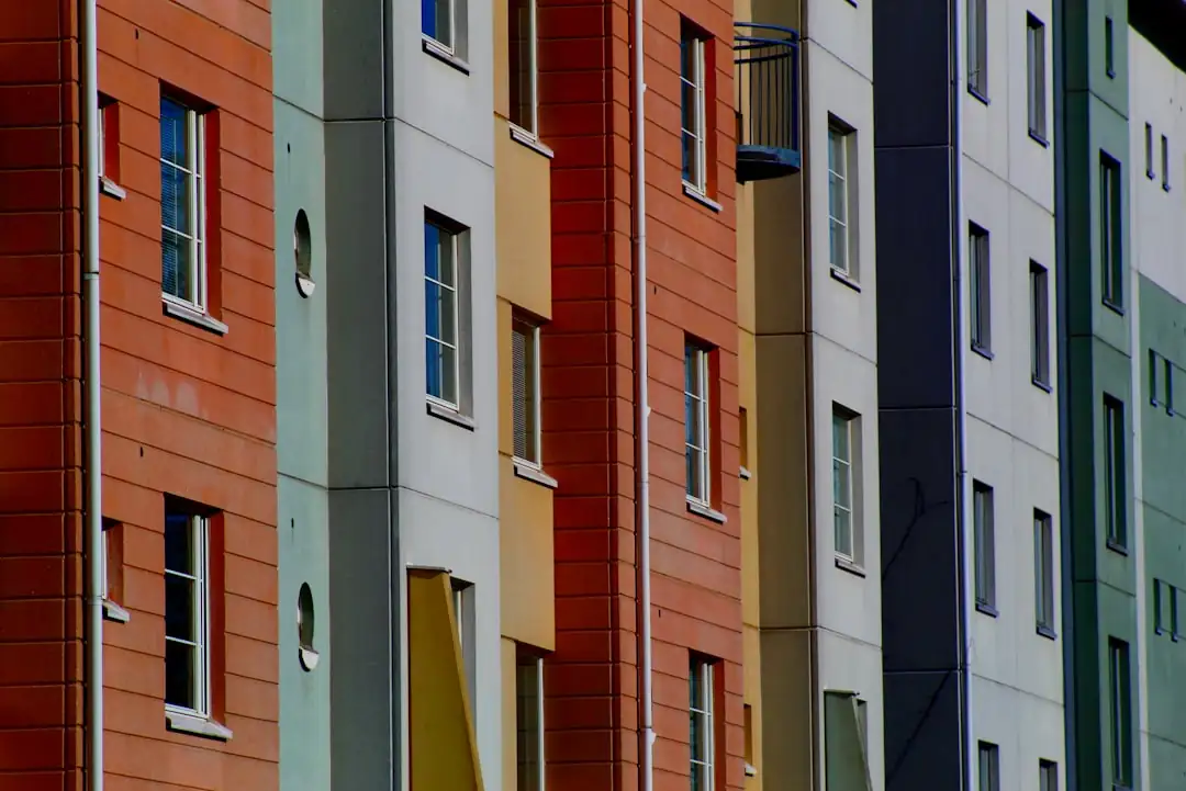 Chantier d’une résidence contemporaine près de la Sarthe, avec rivière, arbres et structure d’immeuble en construction.