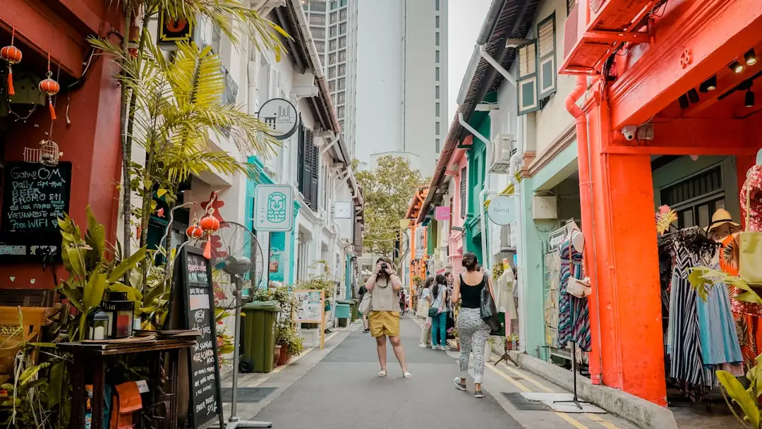 Entrée d’un condominium à Singapour, bordée de végétation tropicale et reliée à une allée piétonne couverte.