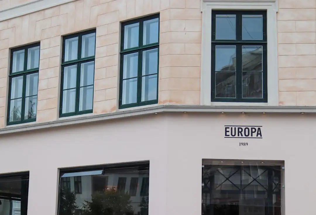Analyste examinant des comptes financiers devant des immeubles de bureaux européens en arrière-plan flou.