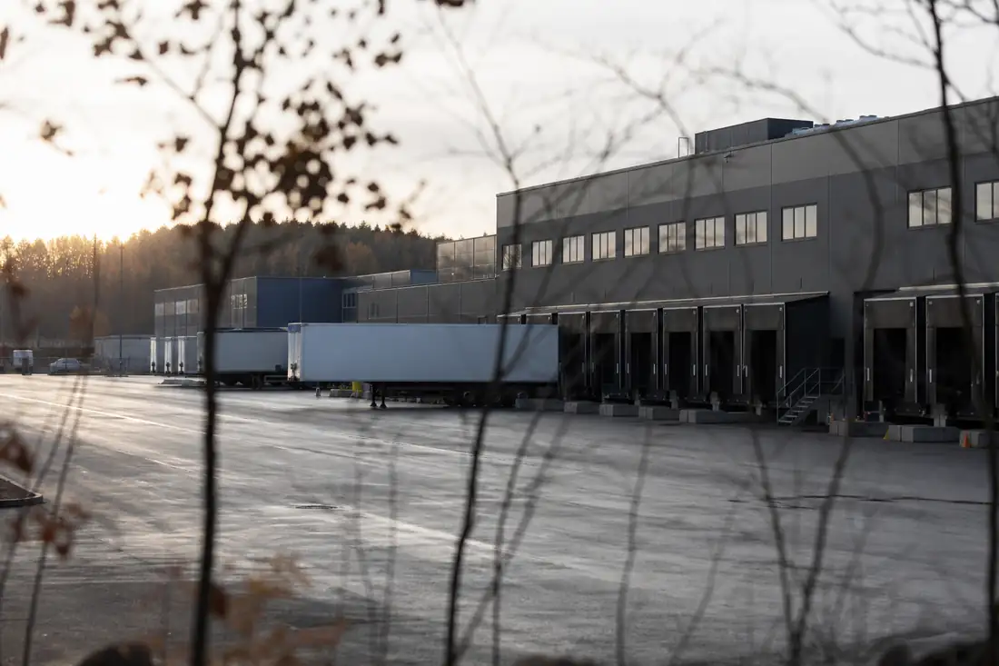Entrepôt logistique moderne avec quais de chargement dans une zone d’activité nordique au petit matin.