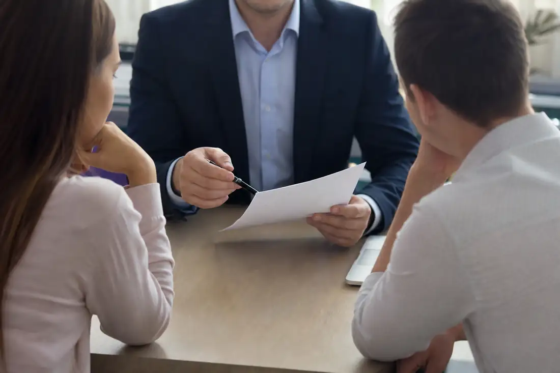 Couple d'emprunteurs consultant un dossier de crédit avec un conseiller bancaire