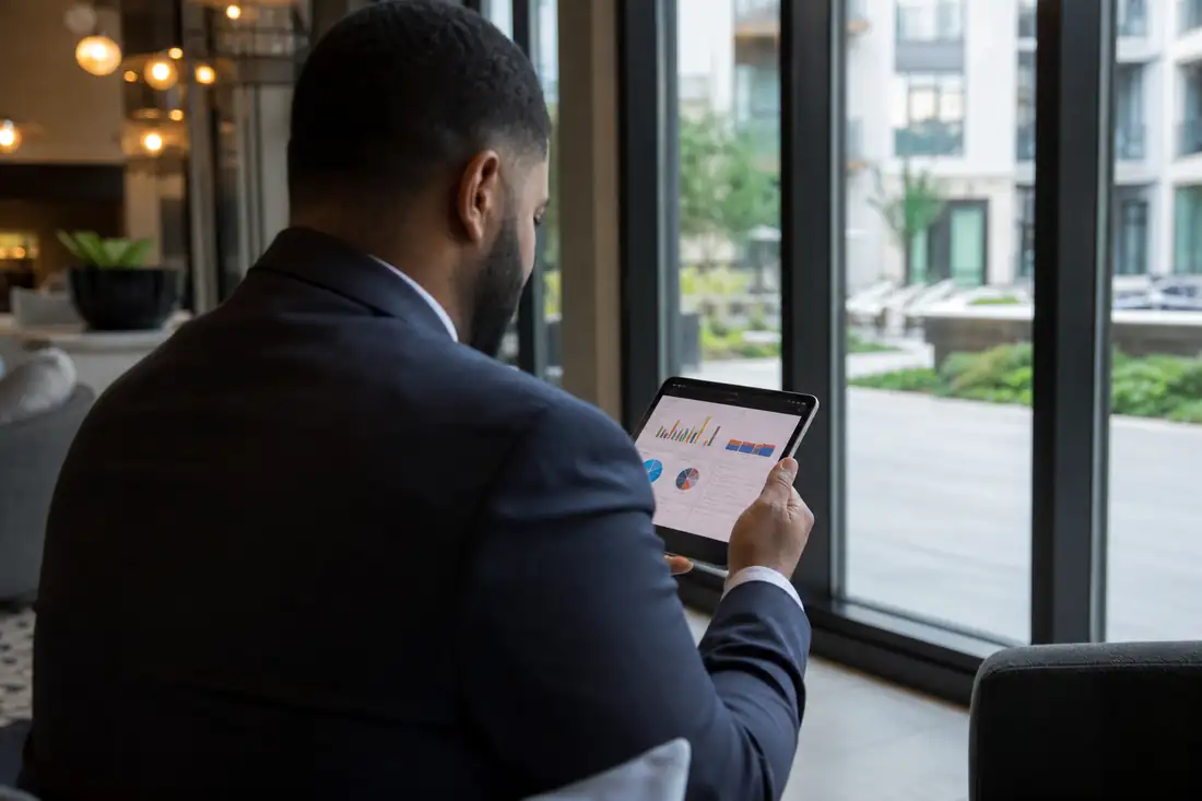 Gestionnaire dans le hall d’un immeuble locatif américain consultant des données financières sur une tablette.