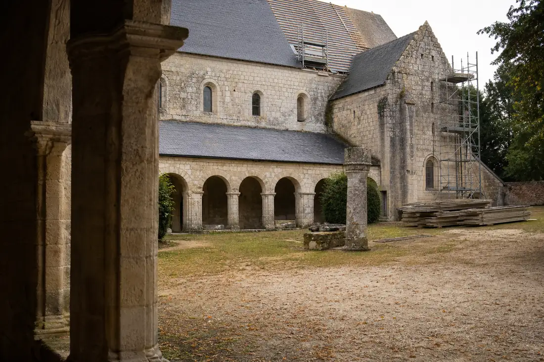 Ancien couvent en pierre dans l’Orne, avec cloître, toiture en ardoise et travaux de réhabilitation discrets.