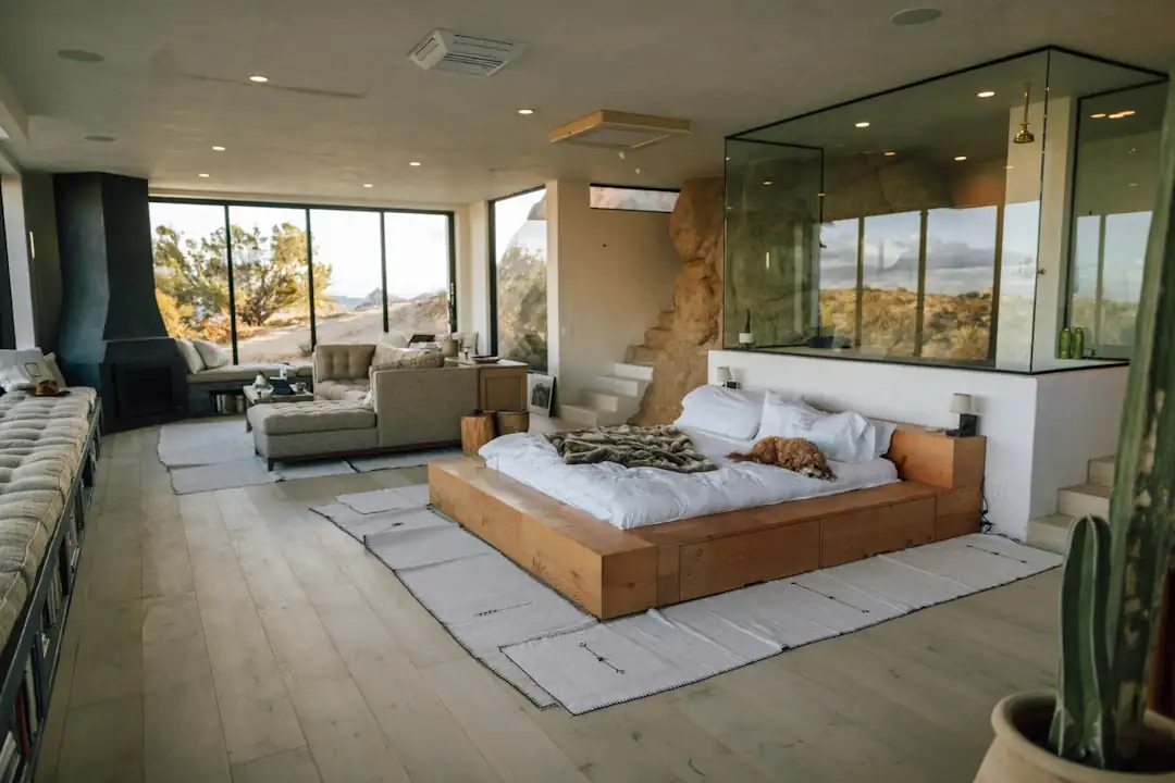Intérieur d’un appartement de grand standing en très haut étage avec baies vitrées sur une métropole au crépuscule.