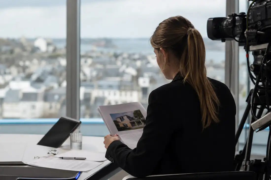 Jeune professionnel de l’immobilier préparant un dossier avant une intervention dans un studio de télévision.