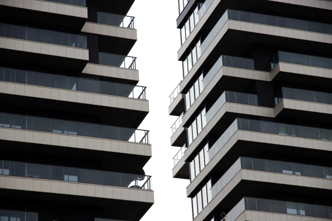 Plateau de bureaux en hauteur avec dossier immobilier sur une table devant les baies vitrées d’une tour.