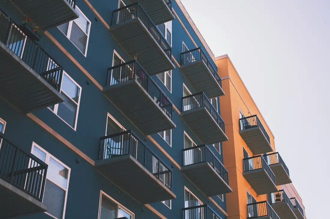 Couple examinant une offre de prêt immobilier et des simulations de mensualités dans un appartement lumineux.